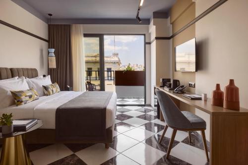 ein Hotelzimmer mit Bett, Schreibtisch und Fenster in der Unterkunft Mural Piraeus Hotel in Piräus