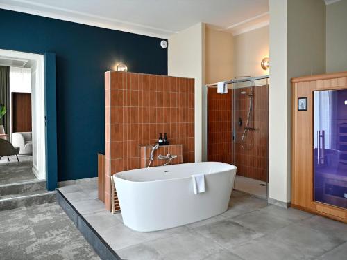 a bathroom with a white tub and a shower at Fletcher Hotel Paleis Stadhouderlijk Hof in Leeuwarden