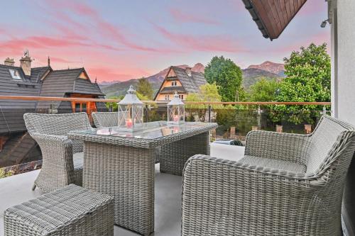 a patio with wicker chairs and a table with a view at Apartamenty Widokowe Pod Lasem in Kościelisko