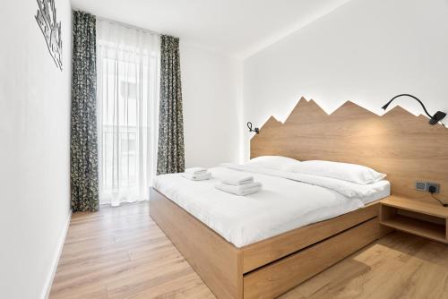a bedroom with a bed with a wooden headboard at Apartmány Krušec by Mountain ways in Plešivec
