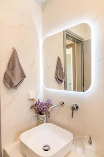 a white bathroom with a sink and a mirror at Aegean Whispers in Agios Fokas