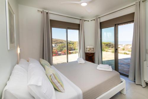 a bedroom with two beds and a large window at Aegean Whispers in Agios Fokas