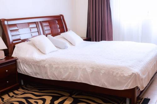 a bed with white sheets and pillows in a bedroom at Mariebu Beach Resort in Buhongo