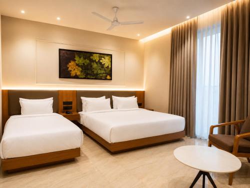 a hotel room with two beds and a table at LUXURIA INN By CHANDAN in Junagadh