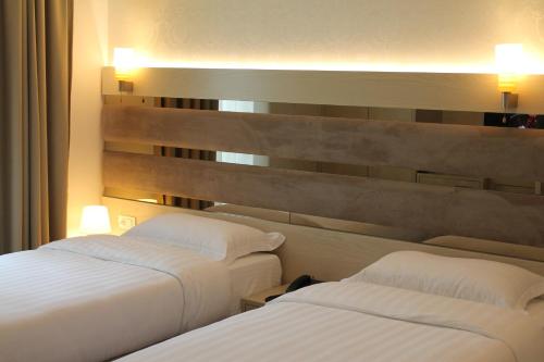 two beds in a hotel room with white sheets at Capital Tirana Hotel Bruçi in Tirana