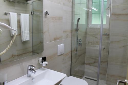 a bathroom with a sink and a glass shower at Capital Tirana Hotel Bruçi in Tirana