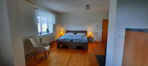 a bedroom with a bed and a chair and a window at Chalupa Lipiny in Nečín