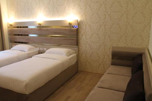 a bedroom with two beds and a couch in it at Capital Tirana Hotel Bruçi in Tirana