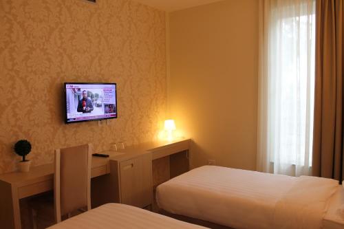 a hotel room with two beds and a tv on the wall at Capital Tirana Hotel Bruçi in Tirana