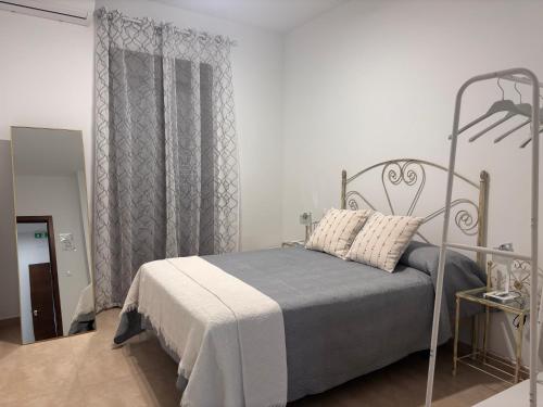 a white bedroom with a bed with a metal frame at El rincón de San Bartolomé in Jerez de los Caballeros