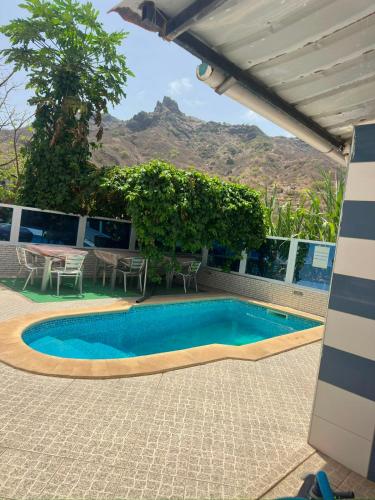 a swimming pool with a table and a mountain in the background at Pensão Simão & Júlia - 8 Quartos in Órgãos