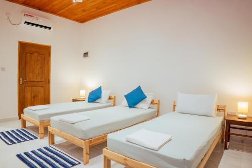 two beds in a room with blue pillows at Neem Tree Boutique Resort in Serukele
