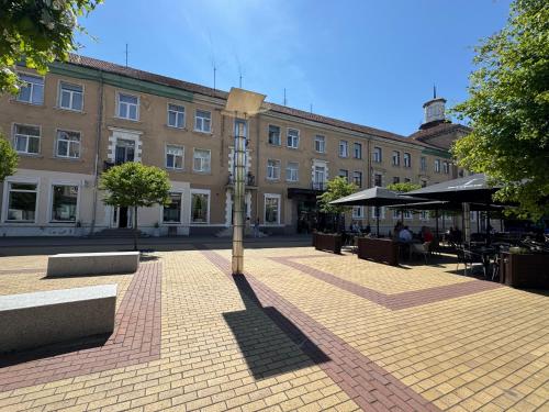 a building with a clock in the middle of a courtyard at Мazvydo Avenue Studio Кlaipeda City Centre in Klaipėda
