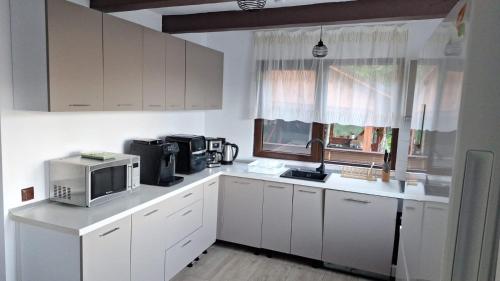 a kitchen with white cabinets and a microwave at Cabana Teo in Valea Ierii