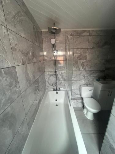 a bathroom with a bath tub and a toilet at Brennan stays contractor professional Friendly in Liverpool