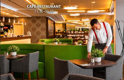 a man standing at a table in a restaurant at Iris Hotel Eden - Czech Leading Hotels in Prague