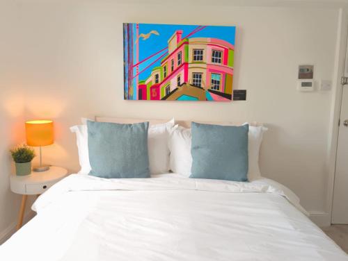 a bedroom with a white bed with a painting on the wall at Upper Rock Brighton – Guest House in Brighton & Hove