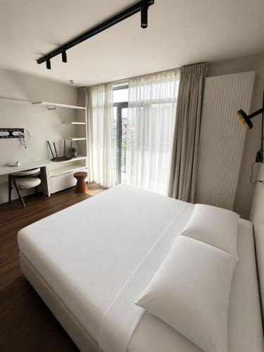 a large white bed in a bedroom with a window at Roxi Roosevelt in Antwerp