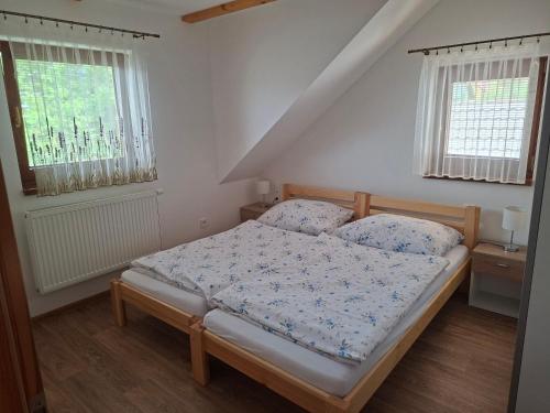 a bedroom with a bed and two windows at Apartmány Švec in Terchová