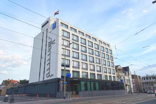 a tall white building with a flag on top of it at TRYP Badhotel The Hague Scheveningen BRAND NEW in Scheveningen