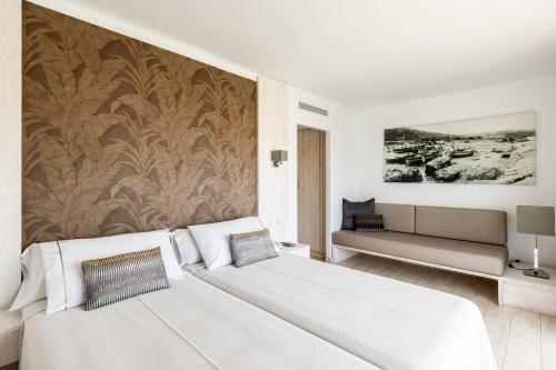 a white bedroom with a large white bed and a wall at Can Miquel in L'Escala
