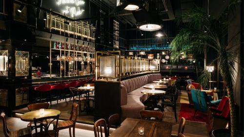 ein Restaurant mit Tischen und Stühlen und einer Bar in der Unterkunft Ruby Mimi Hotel Zurich by IHG in Zürich