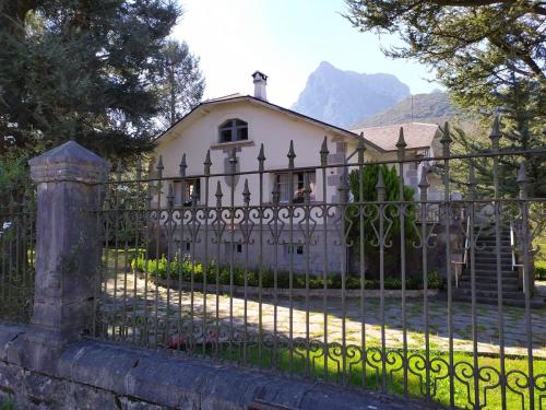 a fence in front of a white house at Casa con bosque en Cantabria in Ramales de la Victoria