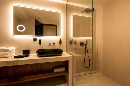 a bathroom with a sink and a shower with a mirror at AVAIA boutique hotel in Nea Moudania