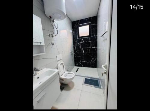 a white bathroom with a toilet and a sink at Cozy Apartments in Ulcinj