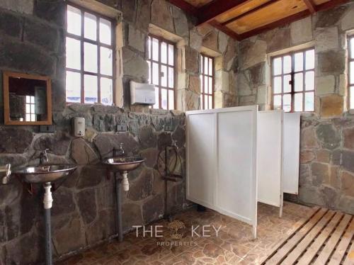 a stone bathroom with two sinks in a stone wall at Refugio de Montaña Placaroja in San José de Maipo