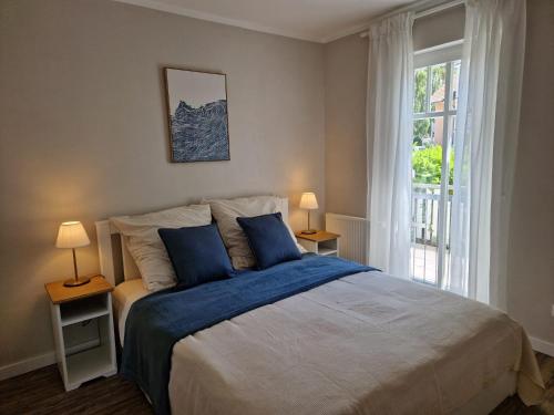 a bedroom with a bed with blue pillows and a window at FeWo Gisa - Graal Müritz in Graal-Müritz