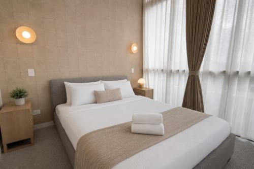 a bedroom with a large white bed and a window at Lumi Residence Robina in Gold Coast