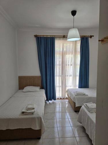 a bedroom with two beds and a window with blue curtains at Golden Pension in Patara