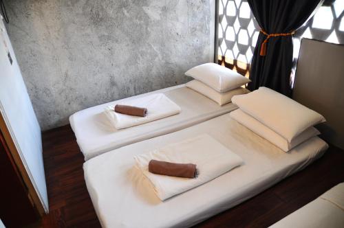 a white bed with three pillows on it at GRAYHAUS INN Ipoh in Ipoh