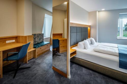 a bedroom with a bed and a desk and a mirror at Hotel Schwan & Post in Bad Neustadt an der Saale