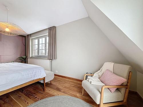 a bedroom with a bed and a chair and a window at Villa Charme - Koksijde in Koksijde