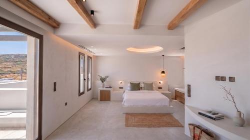 a bedroom with a white bed and a large window at The Lofts Paros Executive Suites in Naousa