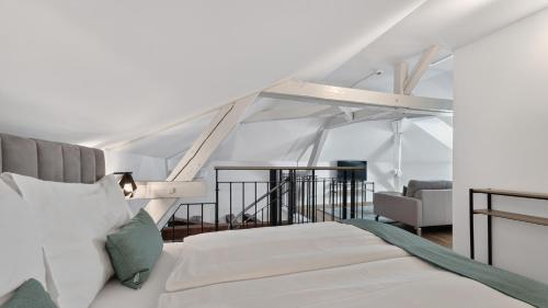 a white bedroom with a bed and a chair at GLANDON Rooms Haldenhof - Self-Check-In in Lucerne