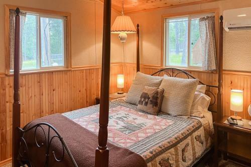a bedroom with a canopy bed with two windows at Mountain Escape in Sturgis