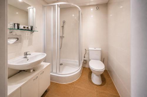 a bathroom with a shower and a toilet and a sink at Hotel Merkur - Czech Leading Hotels in Prague