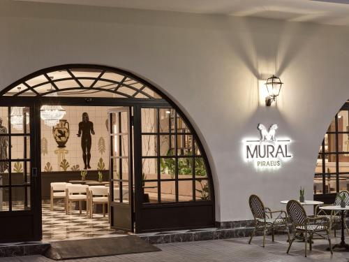 ein Restaurant mit Tischen und Stühlen und einem Schild an der Wand in der Unterkunft Mural Piraeus Hotel in Piräus