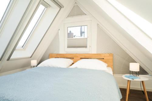 a bedroom with a bed and two windows at Haus 1805 Fehmarn in Fehmarn