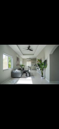 a living room with a ceiling fan and a kitchen at Teika comfort in Kingston