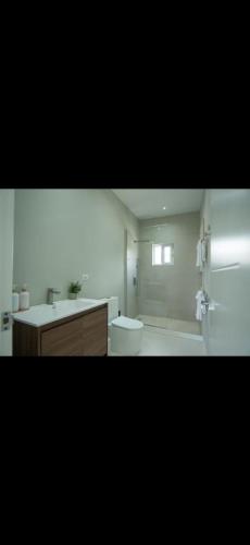 a white bathroom with a toilet and a sink at Teika comfort in Kingston