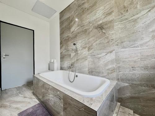 a white bath tub in a bathroom with marble walls at Number 12, Jadde apartments in Sandton