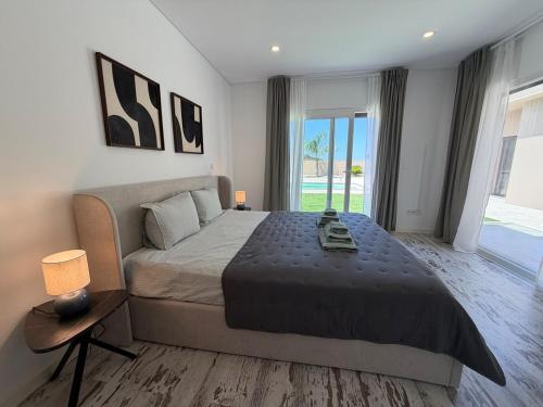 a bedroom with a large bed and a large window at La maison da serra in Quinta do Anjo
