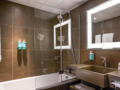 a bathroom with a tub and a sink and a mirror at Novotel Marne La Vallée Collégien in Collégien
