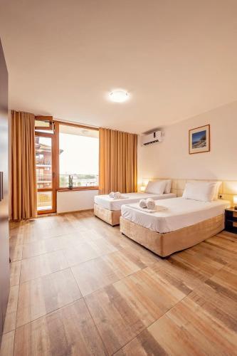 two beds in a large room with a large window at Guest House Elidis in Primorsko
