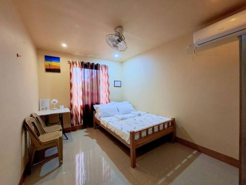 a bedroom with a bed and a desk and a window at Jenalfe Guest House in Camiguin