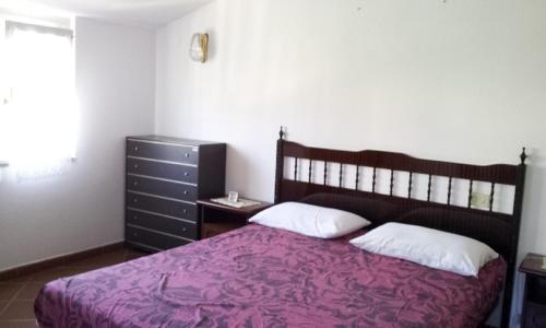 カーラゴノネにあるAppartamento Mauroのベッドルーム1室(紫の毛布とドレッサー付きのベッド1台付)